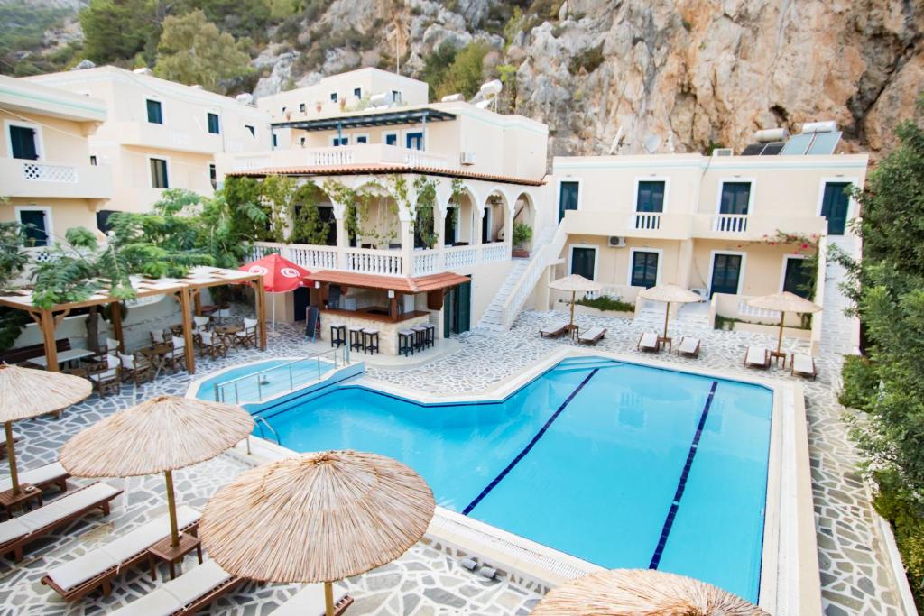 Kyra PanagiaKyra Panagia Hotel的享有酒店游泳池的景色,配有遮阳伞