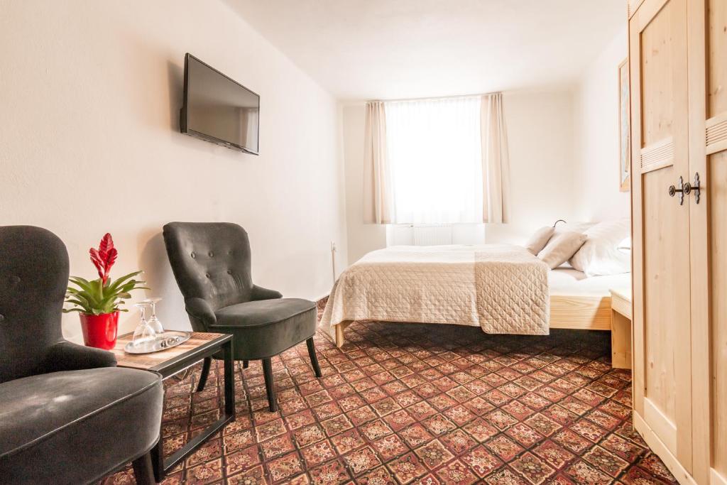 捷克克鲁姆洛夫家庭旅馆的一间卧室配有一张床、两把椅子和一张桌子