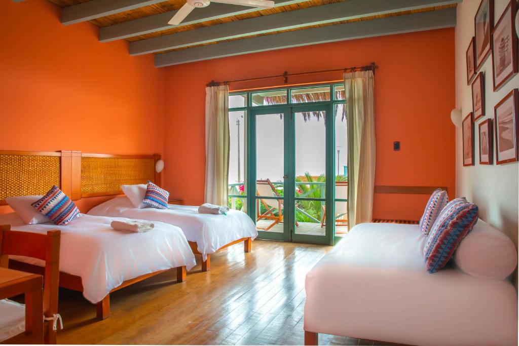 奇卡马港Chicama Boutique Hotel & Spa的橙色墙壁客房的两张床
