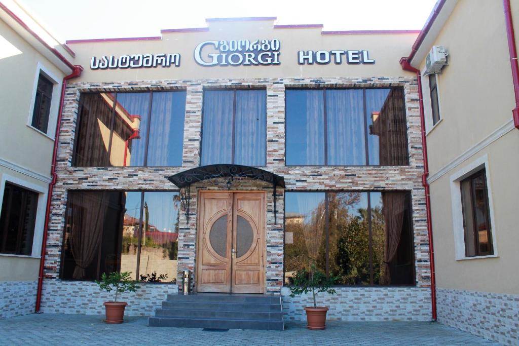 茨卡尔图博Hotel Giorgi的前面有木门的建筑