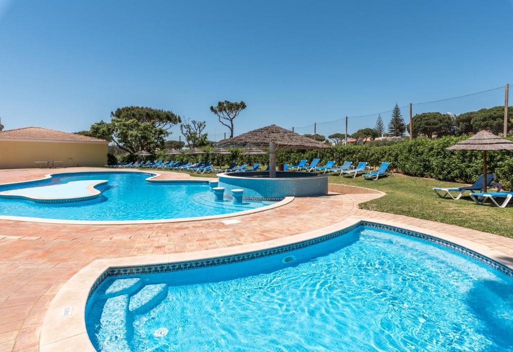 维拉摩拉Browns Sports Resort的度假村的游泳池,配有椅子和遮阳伞