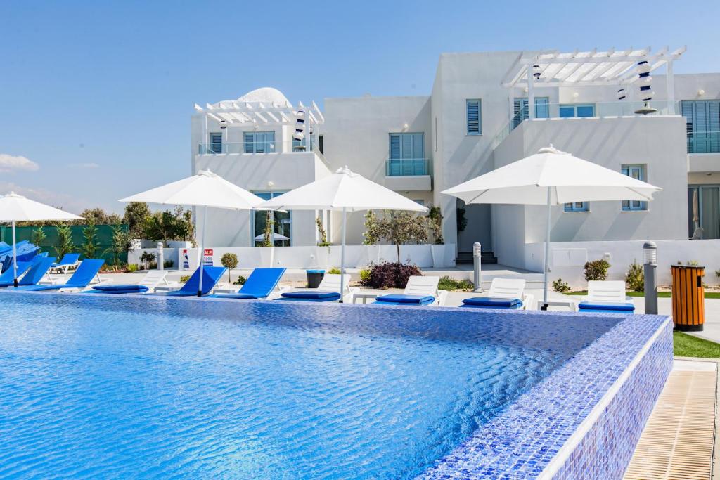 帕福斯Blue Diamond Beach Villas的一个带躺椅和遮阳伞的游泳池