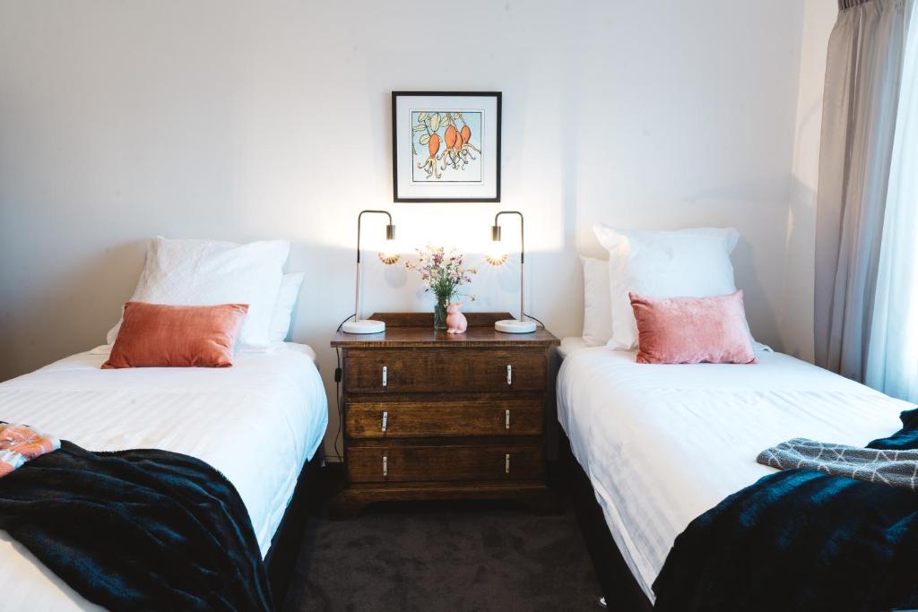 朗塞斯顿索司林恩度假屋的一间卧室配有两张床和一个带鲜花的梳妆台。