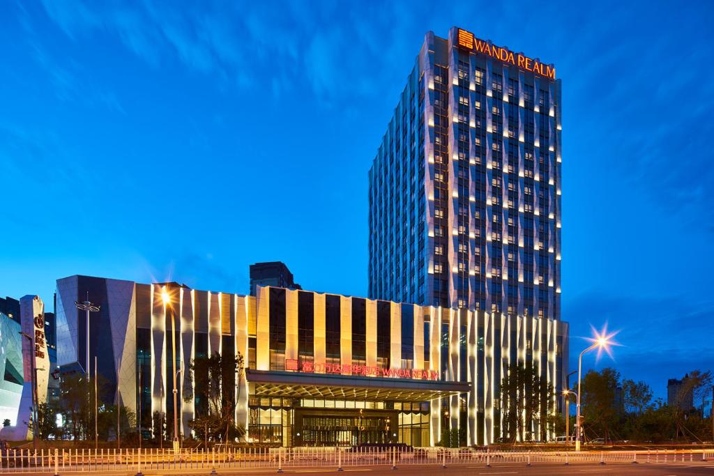 齐齐哈尔齐齐哈尔万达嘉华酒店的一座高大的建筑,晚上有灯