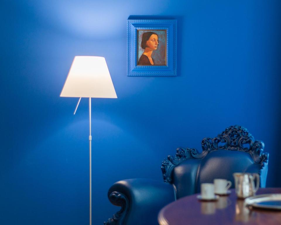 的里雅斯特ViandanteHome, Luxury Rooms的蓝色的客房配有桌子和灯具