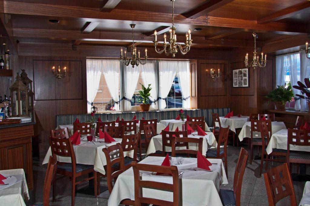 文西德尔Hotel Albergo Mamma Rosa的一间设有白色桌椅和窗户的用餐室