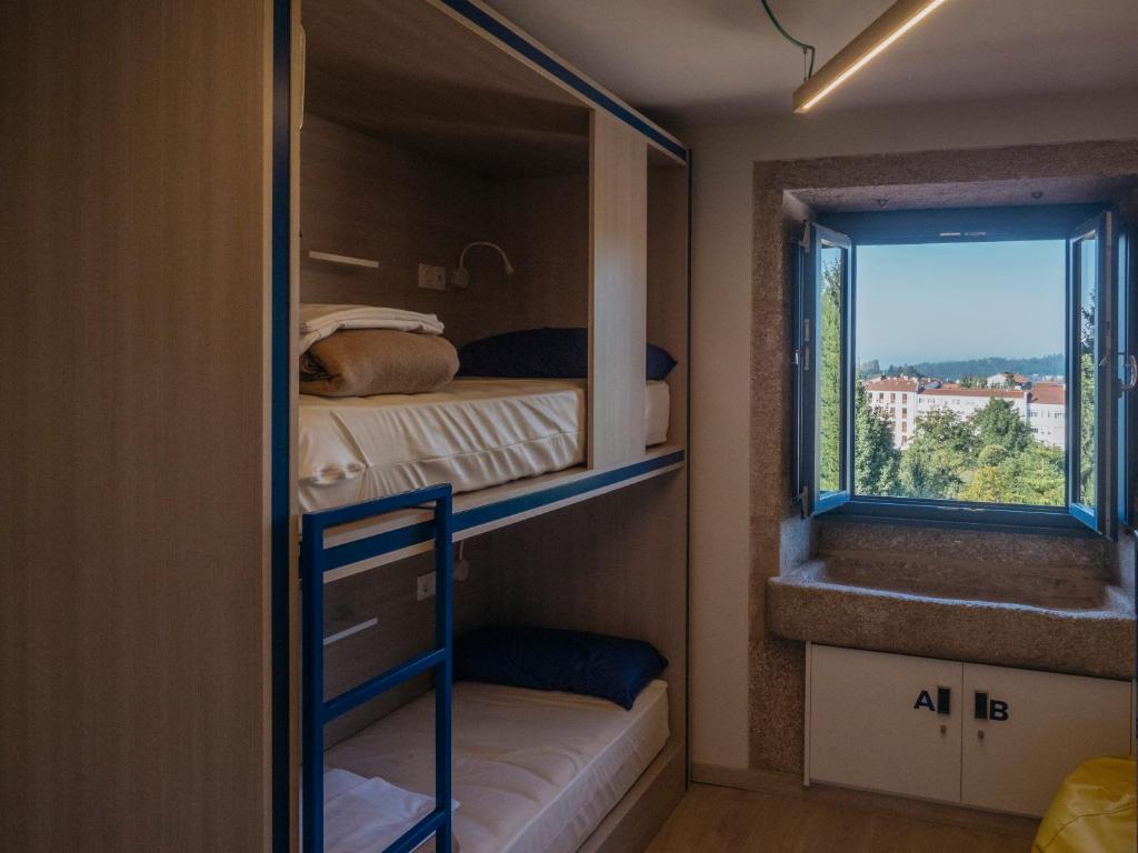 圣地亚哥－德孔波斯特拉Santiago KM-0的小房间设有两张双层床和窗户