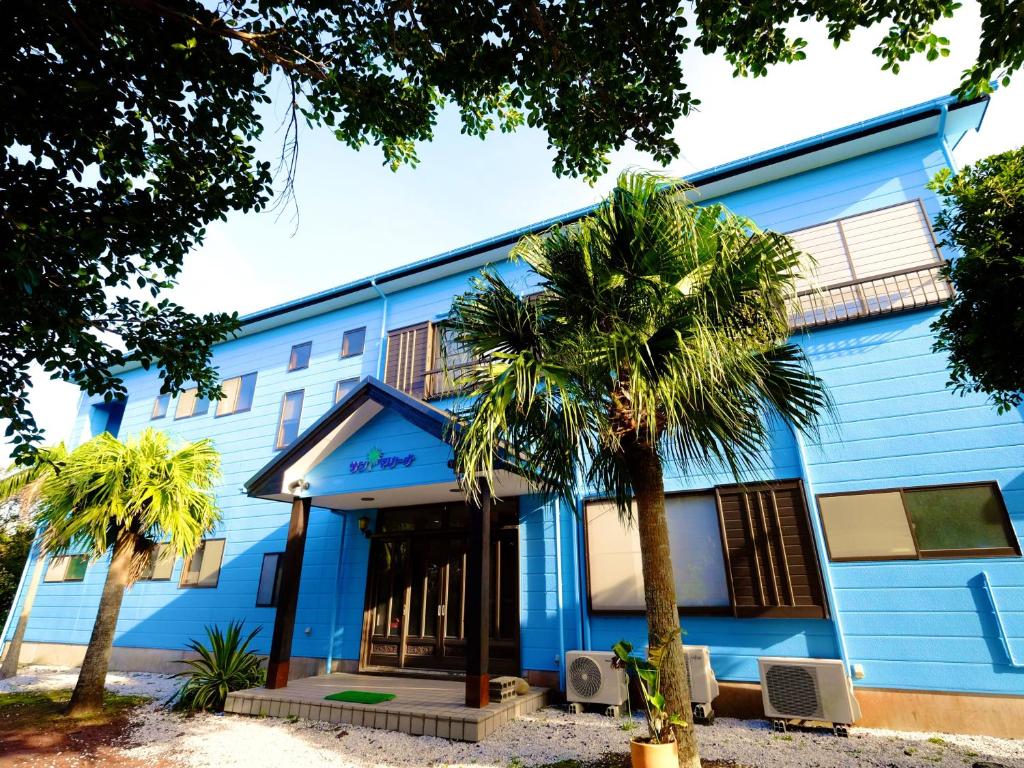KaminatoKokumin Shukusha Sun Marina的一座蓝色的建筑,前面有棕榈树