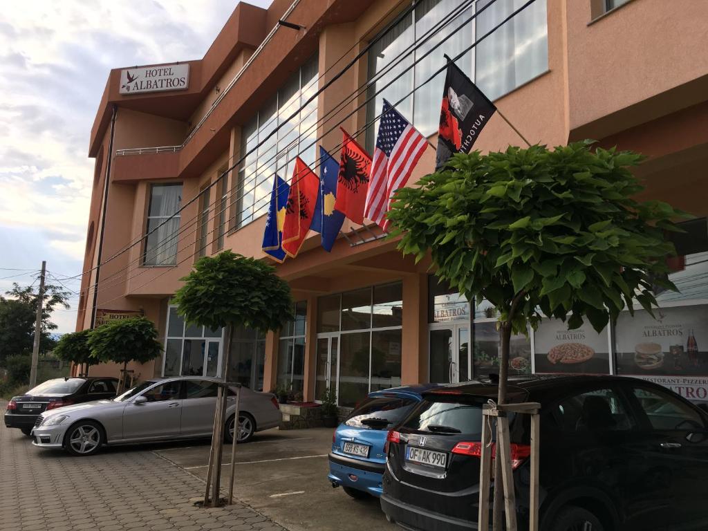 普里兹伦信天翁酒店的一座有旗帜的建筑,门前有汽车