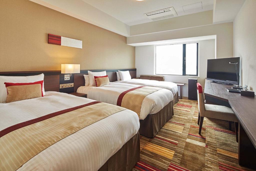 流山Hotel Lumiere Grande Nagareyama-Otakanomori的酒店客房设有两张床和一台平面电视。