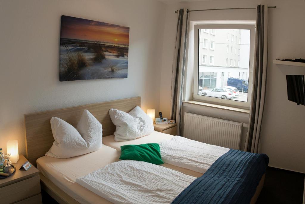 不来梅港Hotel & Apartment Am Theaterplatz的一间卧室配有一张带白色床单的床和一扇窗户。
