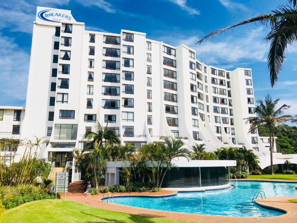 德班Breakers Resort Apartments的一座白色的大建筑,前面设有一个游泳池