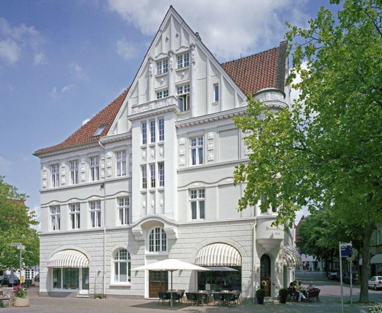 巴特萨尔茨乌夫伦小格鲁纳尔酒店及咖啡馆的一座白色的大建筑,前面设有桌子