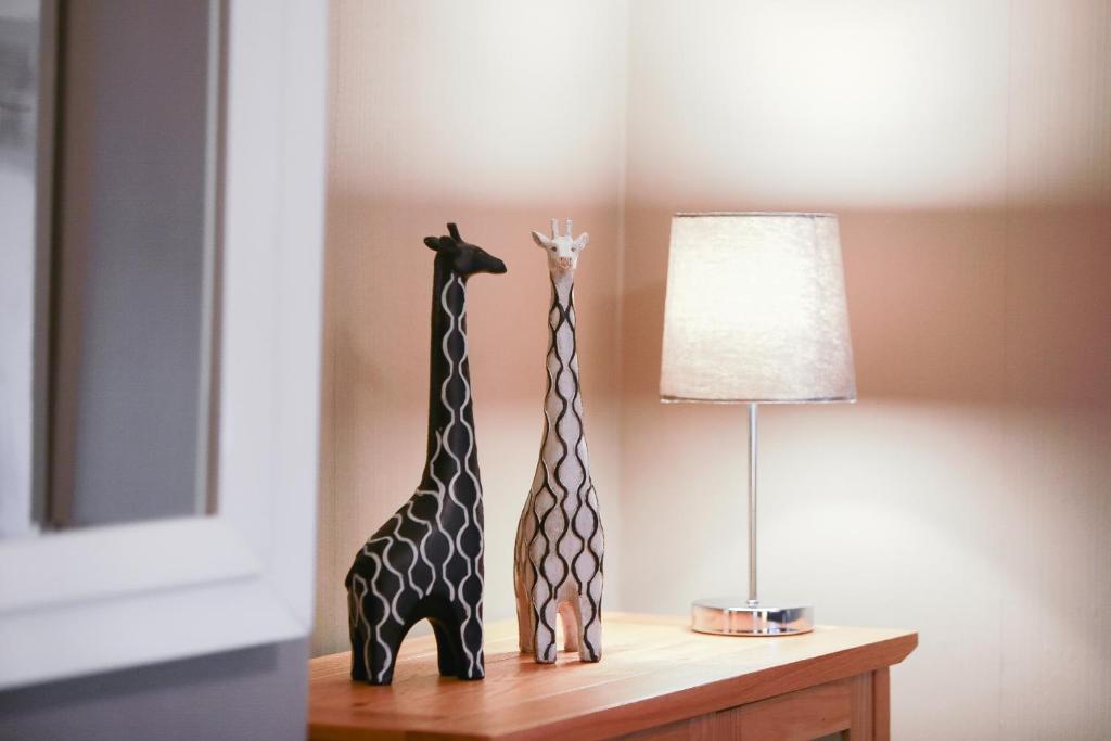 切斯特Zoo House Chester的两座长颈鹿雕像坐在台灯旁边的桌子上