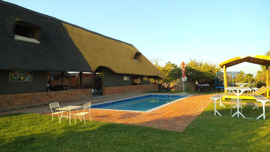 GrootfonteinPondoki Rest Camp的一座带桌椅的游泳池以及一座建筑