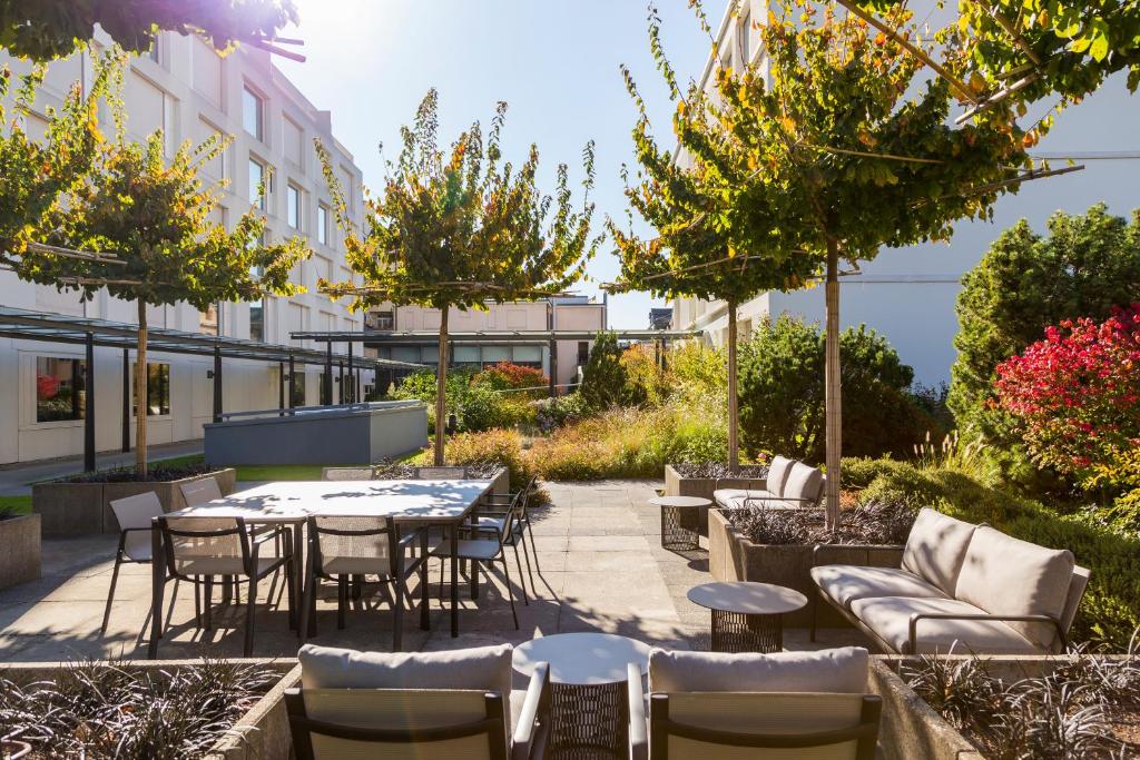巴塞尔欧洲巴塞尔铂尔曼酒店的户外庭院配有桌椅和树木。