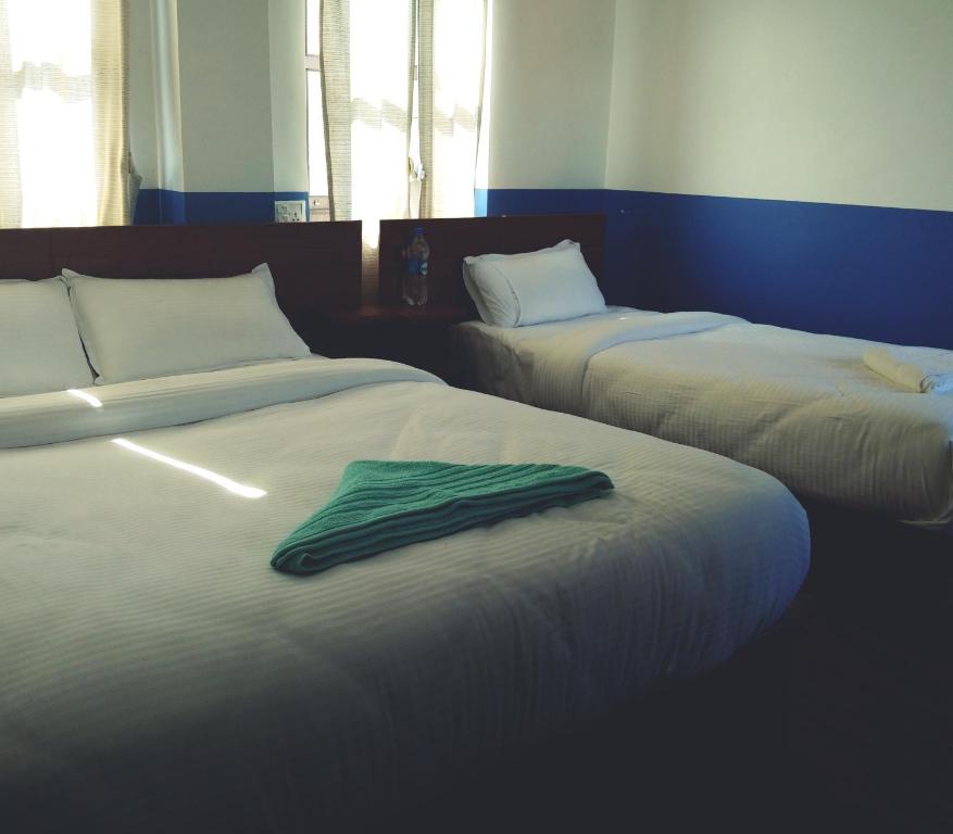 班迪普尔Good Hotel的客房内的两张床,上面有绿毛巾