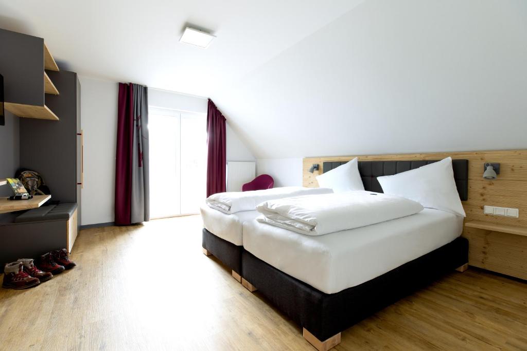 维林根K1 Hotel Willingen的一间卧室配有一张带白色床单的大床
