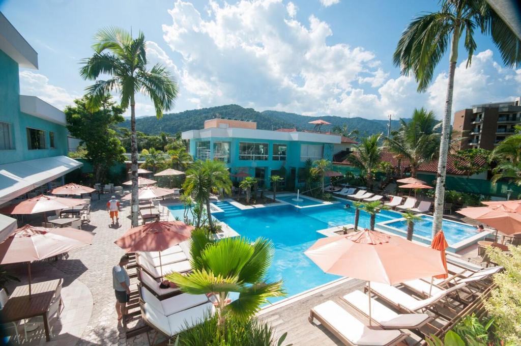 卡拉瓜塔图巴Hotel Port Louis的一个带椅子和遮阳伞的游泳池的度假酒店