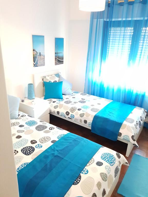 塞图巴尔Apartamento Sado的配有蓝色窗帘的客房内的两张床
