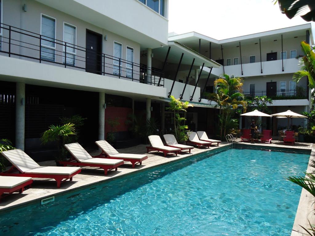 暹粒MEN之温泉度假村（盖伊酒店）的一个带躺椅的游泳池和一间酒店