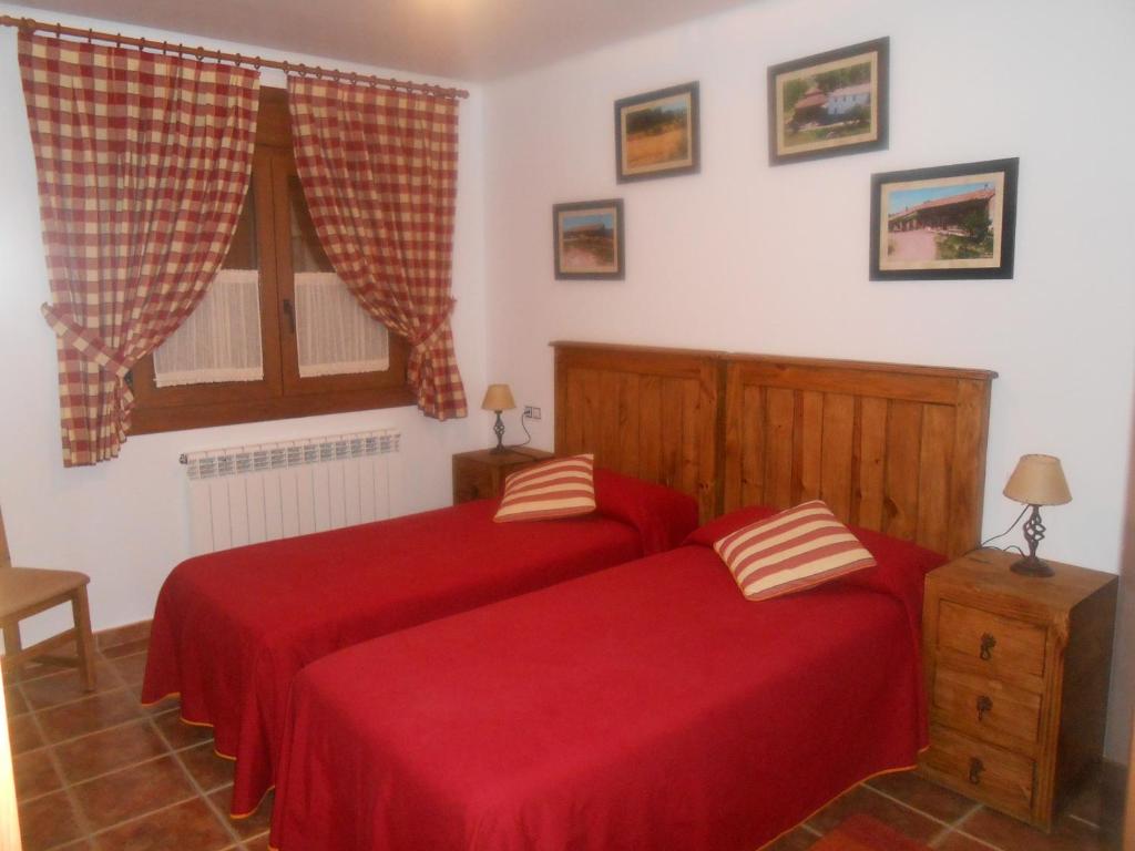 La Virgen de la Vega玛丽亚别墅的卧室内的两张床,配有红色床单