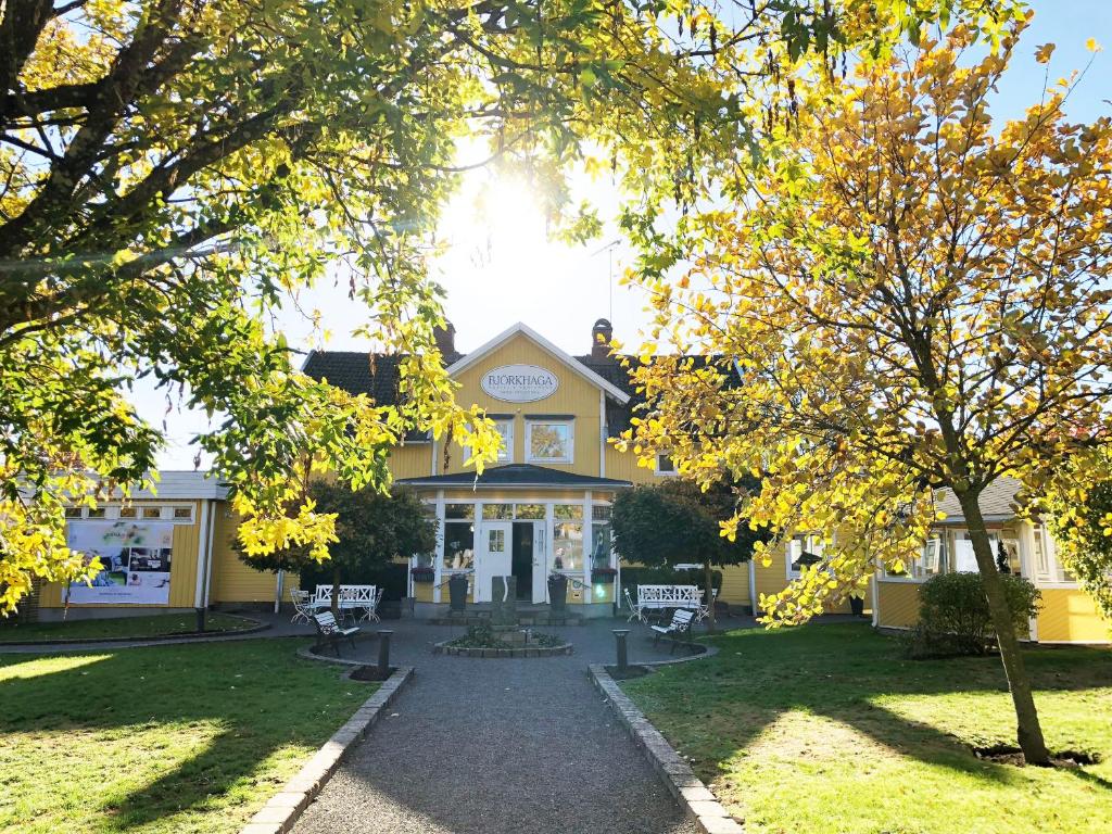 穆尔舍Hotell Björkhaga的前面有树木的黄色建筑