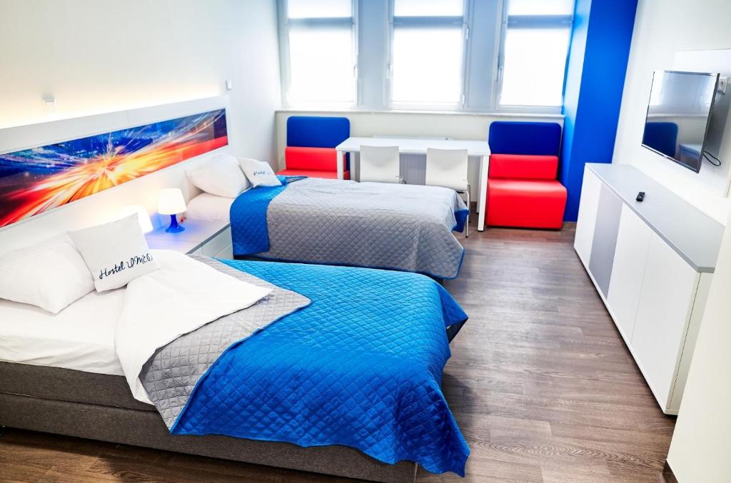 罗兹Hostel Umed的配有两张红色椅子的房间内的两张床