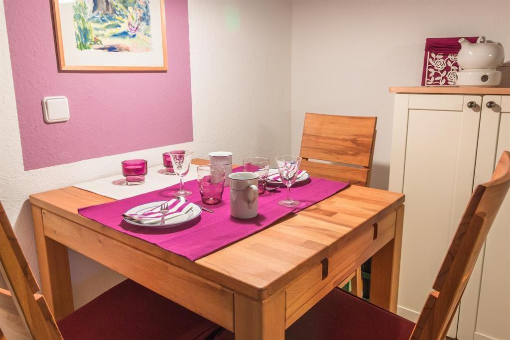基尔Ferienwohnung Küssner的一张木桌,上面放有酒杯和盘子