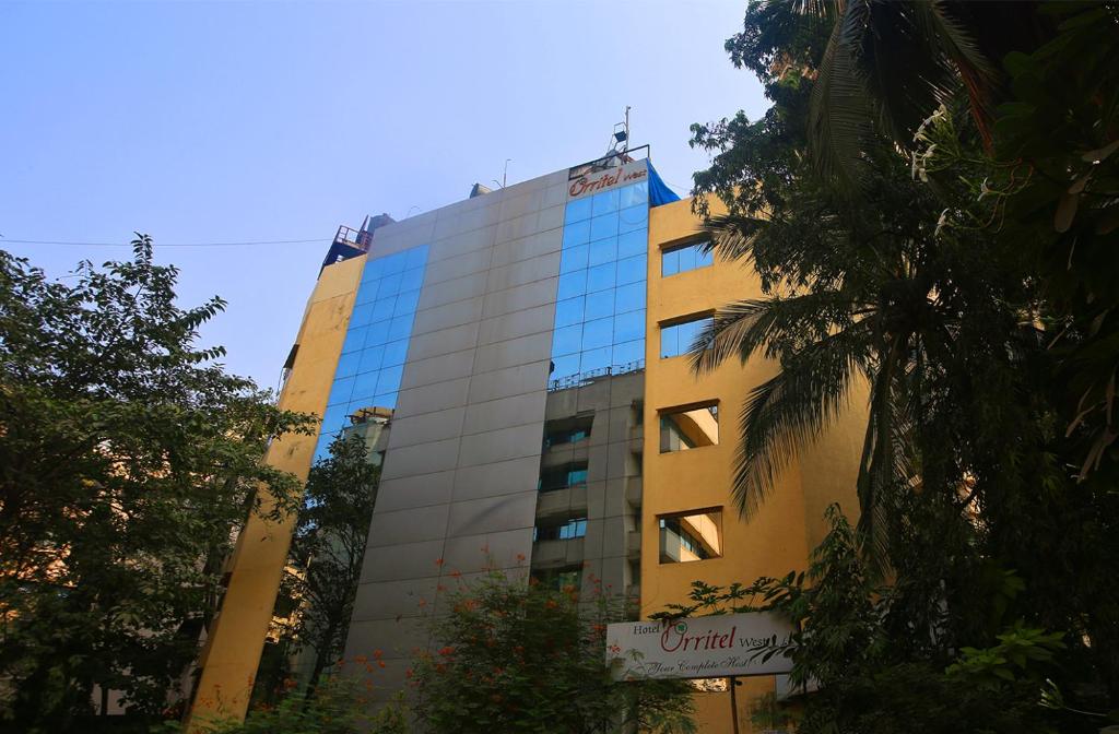 孟买Hotel Orritel West的一座高大的黄色建筑,上面有标志