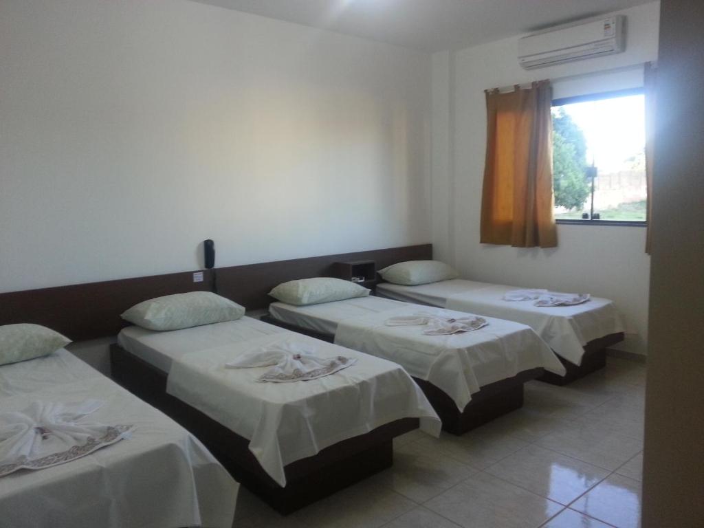 伊瓜苏沙兰迪酒店的带三张床和窗户的客房