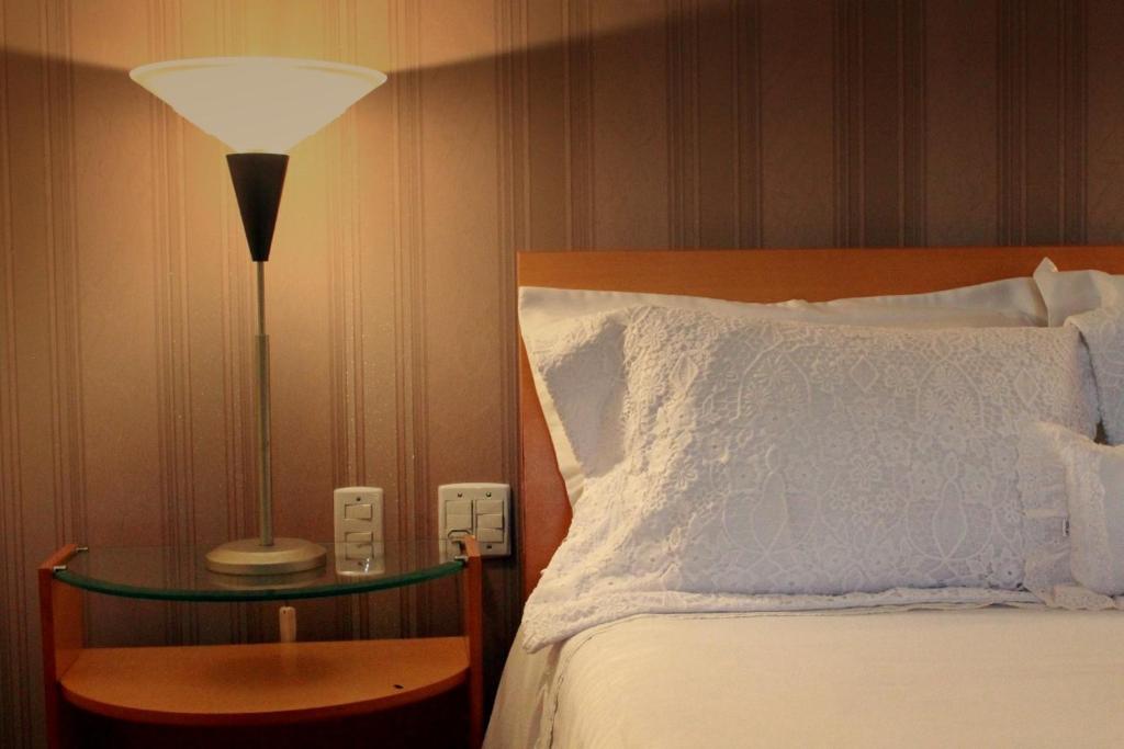 伊塔佩鲁纳Hotel Caiçara Bistrô e Eventos Ltda的一间卧室配有一张床和一张桌子上的台灯