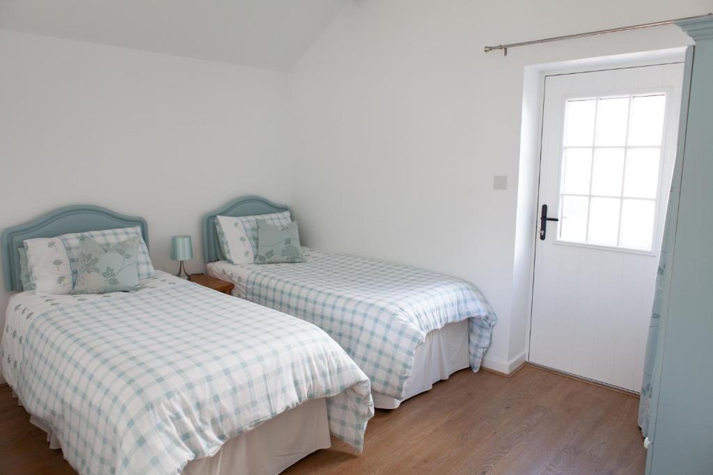 WhitegateElm Cottage Touring Park的一间卧室设有两张床和一扇门
