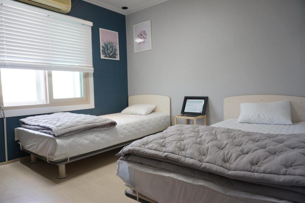 釜山AIRPORT Guesthouse的一间卧室设有两张床和窗户。