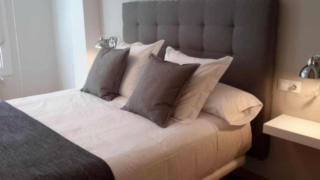 卢戈APARTAMENTOS PORTA NOVA的一间卧室配有带白色床单和枕头的床。