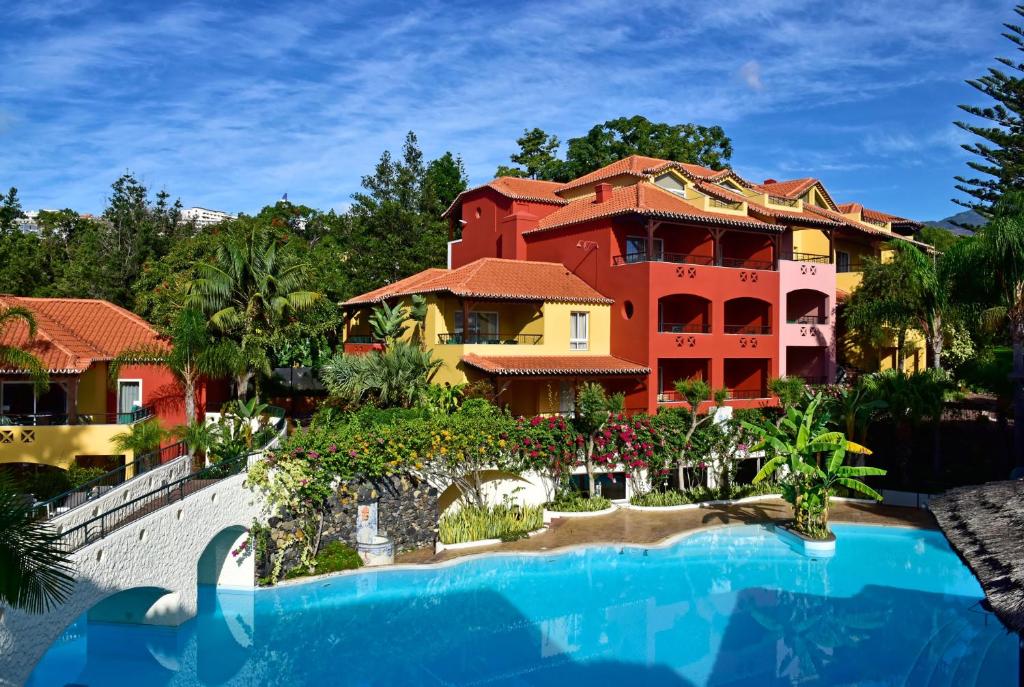 丰沙尔Pestana Village Garden Hotel的一座带游泳池的度假村,位于一座建筑前