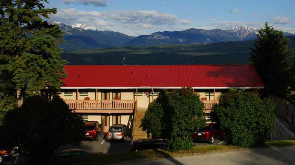 镭温泉Rocky Mountain Springs Lodge的一座有汽车停放在停车场的山间建筑