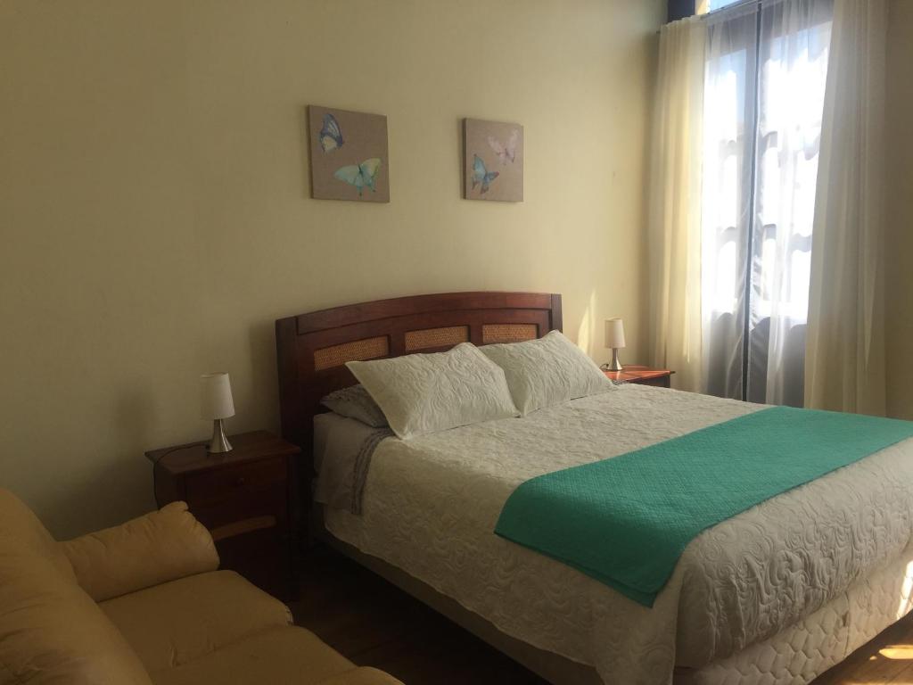 瓦尔帕莱索Hostal Rama & CaStle的一间卧室配有一张床、一张沙发和一个窗口