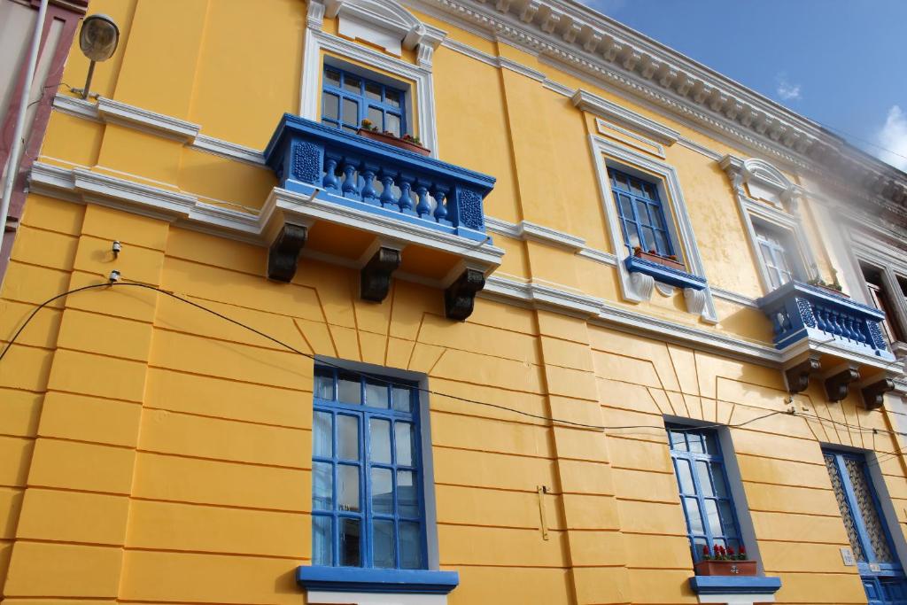 拉塔昆加Hostal Café Tiana的黄色的建筑,设有蓝色的阳台和窗户