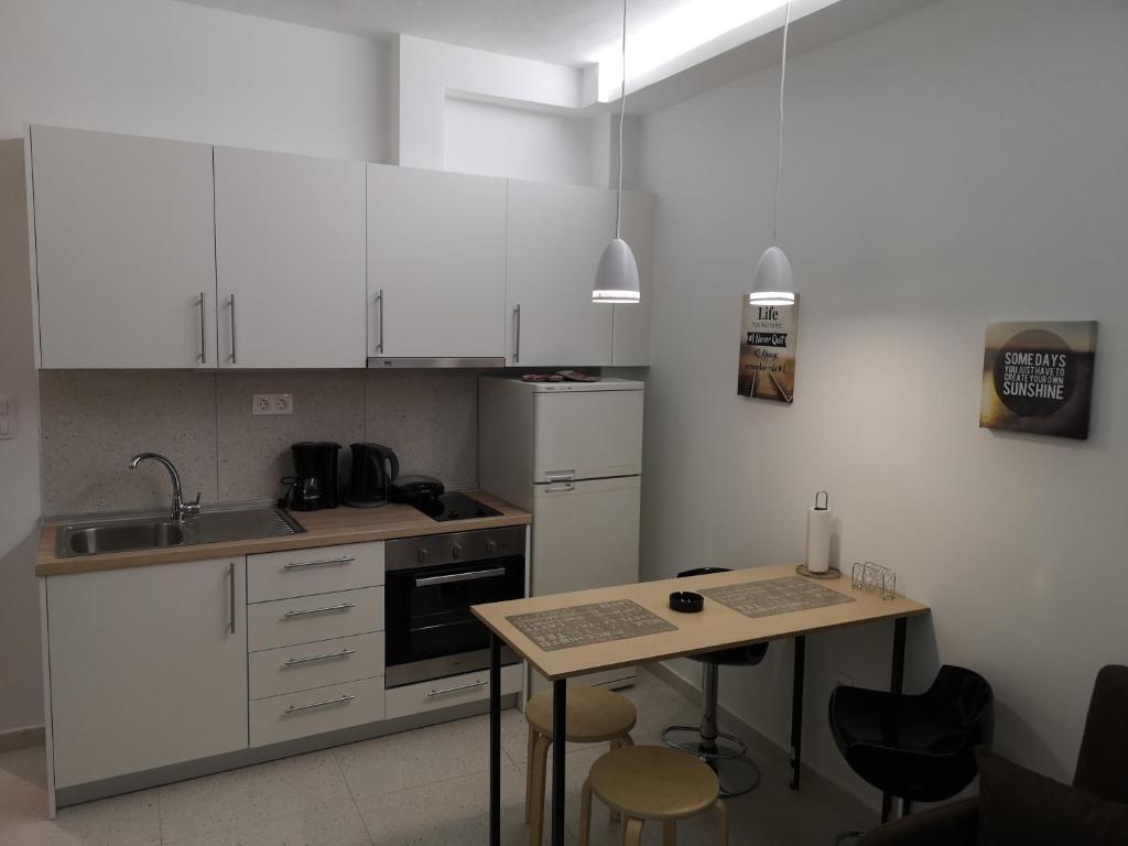 塞萨洛尼基Dimitris House 7的厨房配有白色橱柜和桌椅