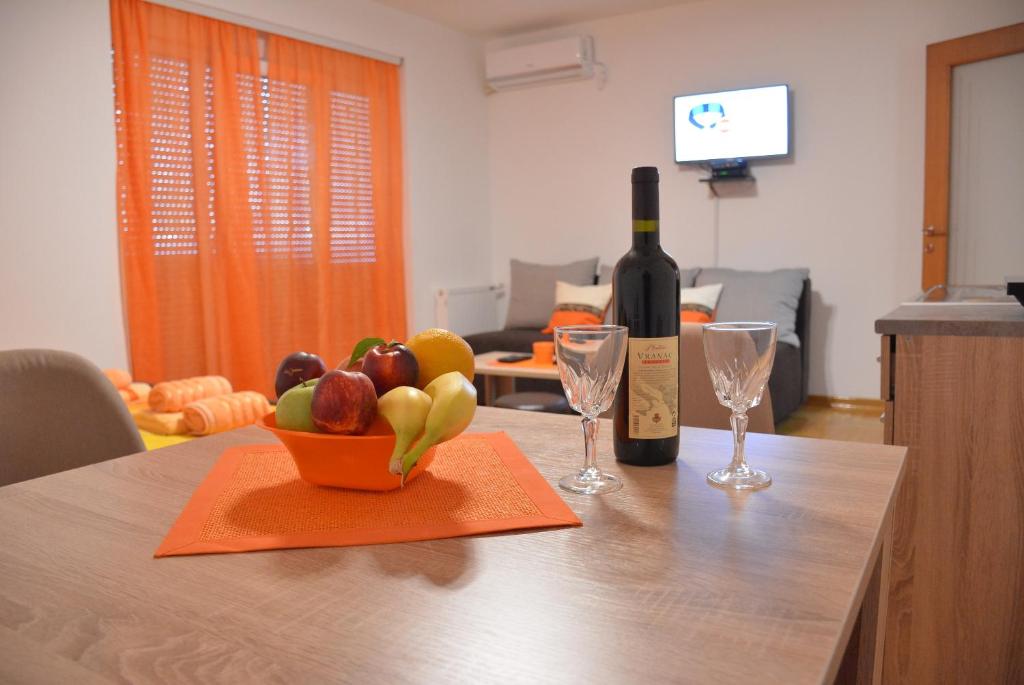 弗尔尼亚奇卡矿泉镇Apartman Radmanovac的一瓶葡萄酒和一碗水果放在桌子上