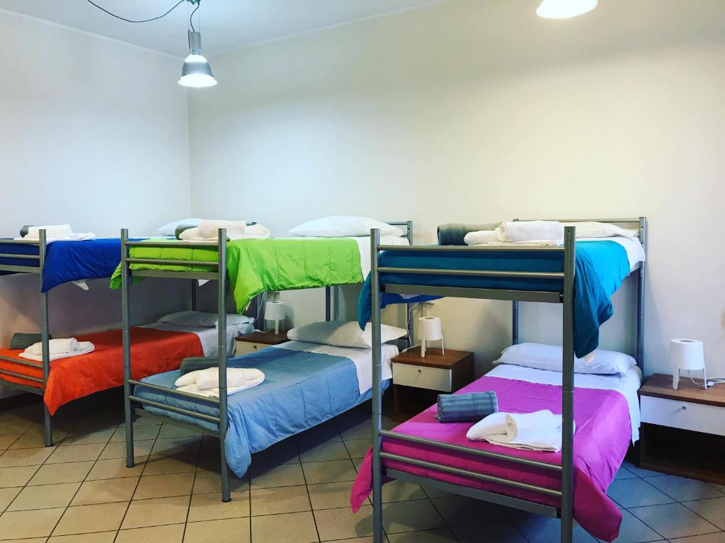 比耶拉Albergo e Ostello della gioventù Biella centro storico的客房设有三张双层床,配有不同的彩色床单