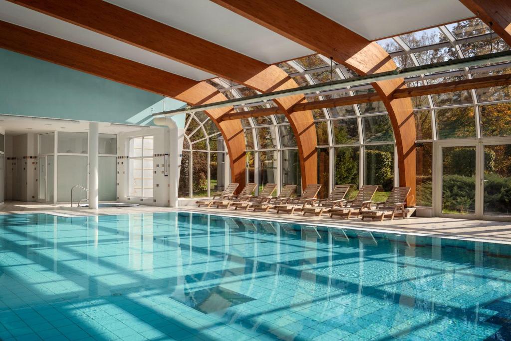卡罗维发利无忧宫温泉度假酒店的一个带椅子和窗户的大型游泳池