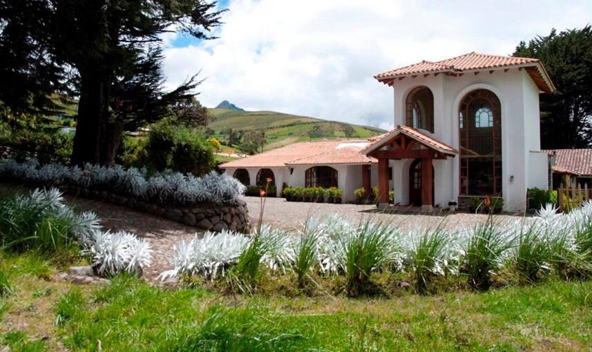 Hacienda Santa Ana圣安娜大庄园酒店的一座房子,前面有一个白色花卉的花园