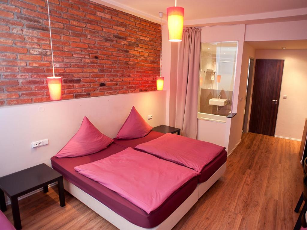 布拉格普尔普尔酒店的卧室配有粉红色的床铺和砖墙