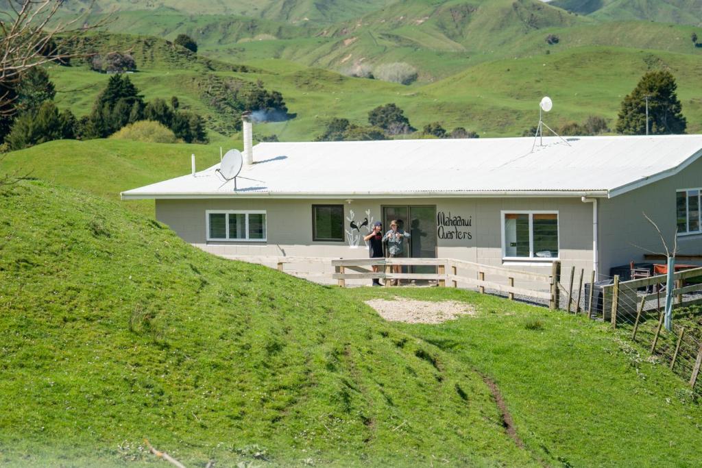 TinirotoMahaanui Quarters Farmstay的山坡上的房子,两个人站在门口