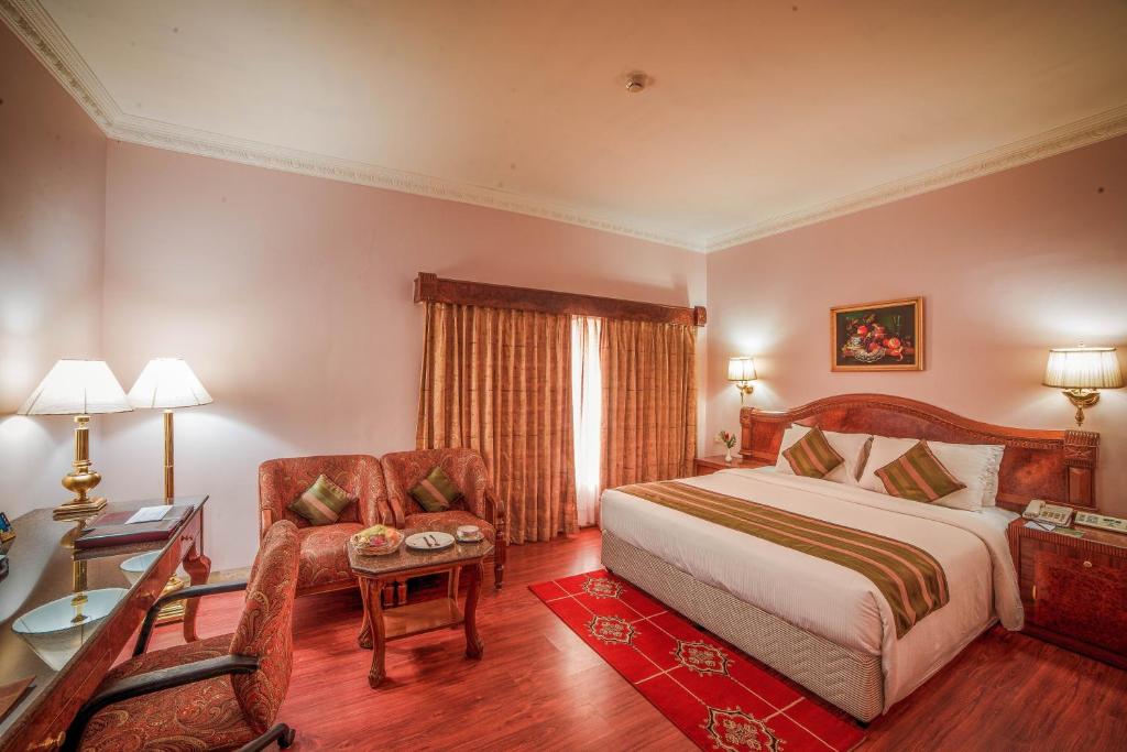 钦奈Raj Park Hotel Chennai的一间卧室配有一张床、一把椅子和一张书桌