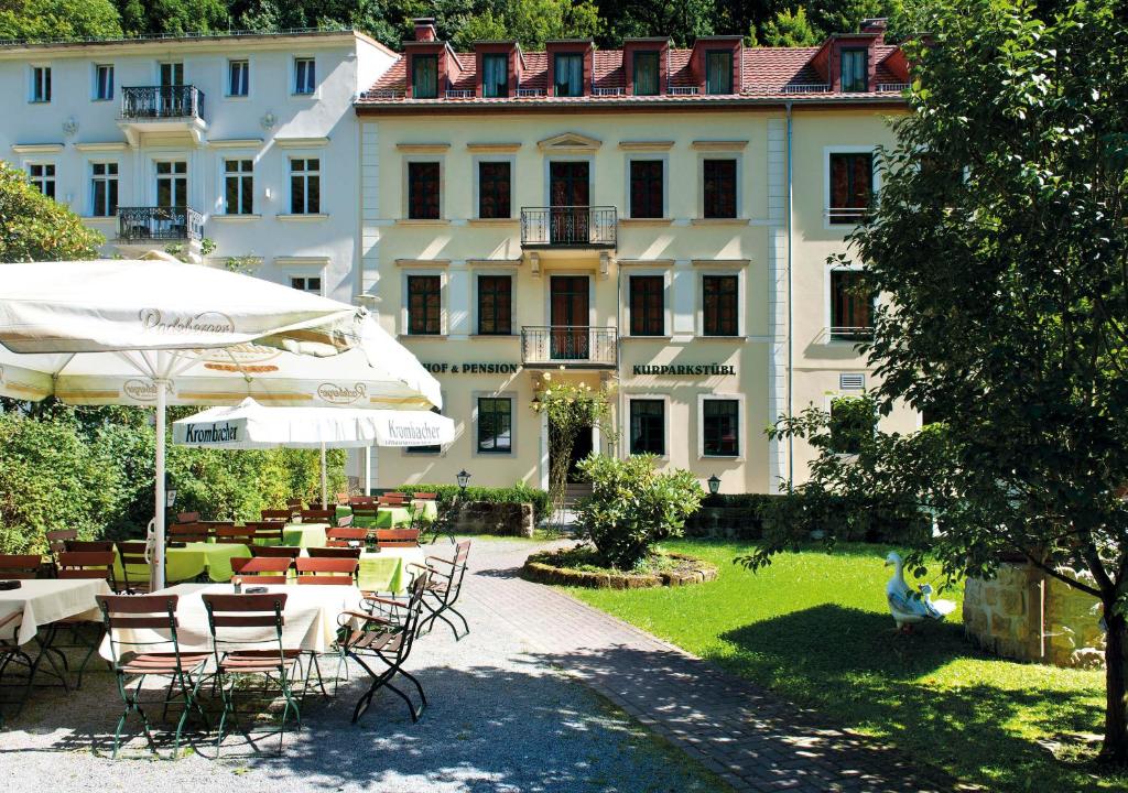 巴特尚道Kurparkstübl Bad Schandau的酒店配有桌椅和遮阳伞。