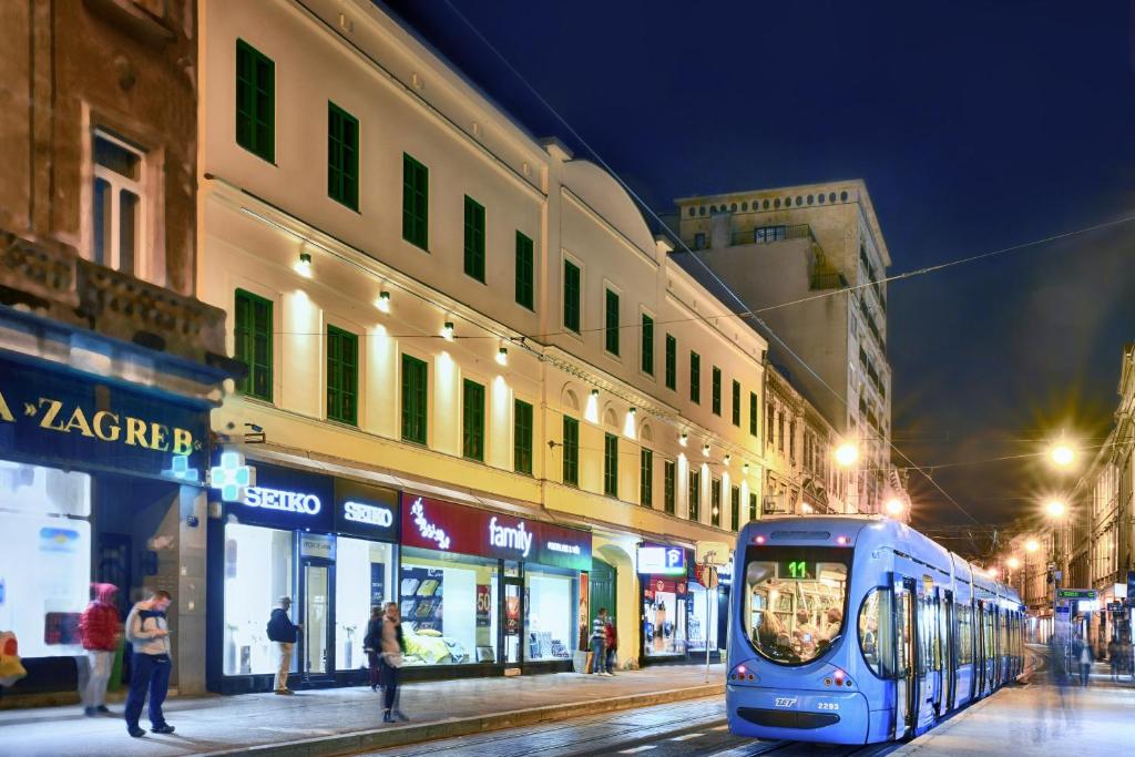 萨格勒布Hotel PARK 45的夜行在城市街道上的蓝色火车