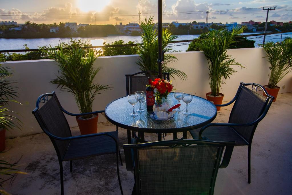 女人岛Suite Isla Mujeres的阳台上的桌子上摆放着酒杯和鲜花